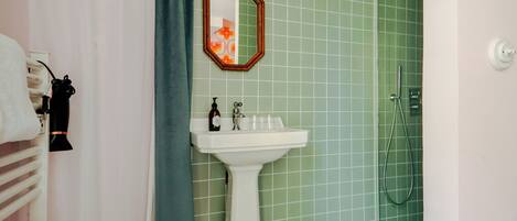 A bathroom with a sink, mirror, and shower.