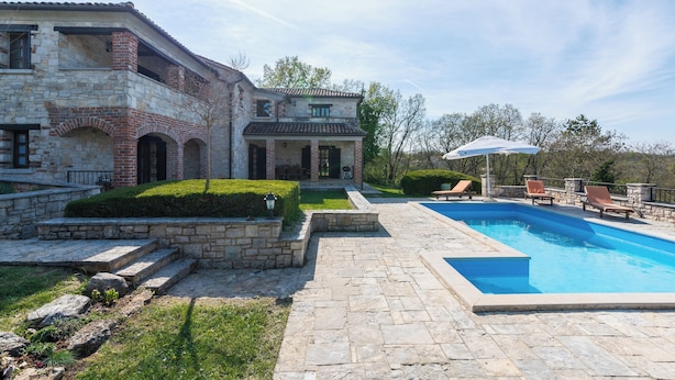 A stone building with a swimming pool, steps, and outdoor seating.