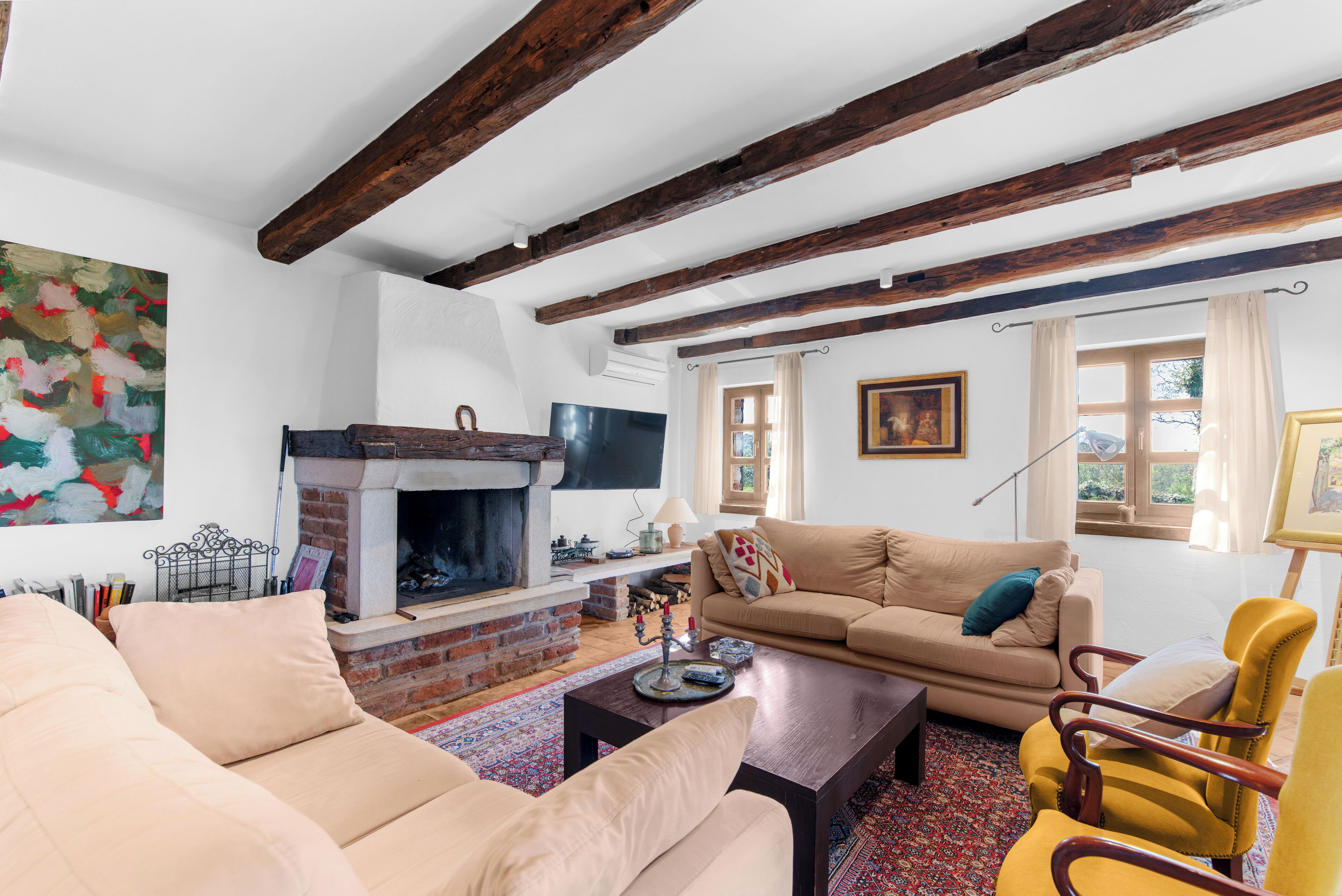 A cozy living room with a fireplace, a sofa, a coffee table, and a yellow armchair.