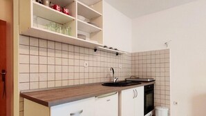 A modern kitchen with white cabinetry, a wooden countertop, and a tiled backsplash.
