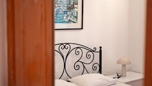A bedroom with a bed, a nightstand, a lamp, and a framed picture on the wall.