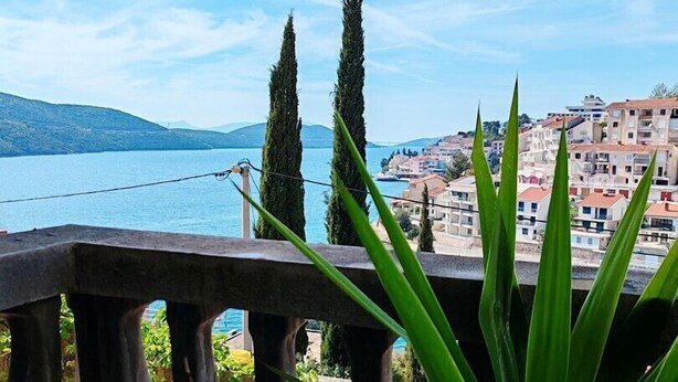 A balcony with a view of a body of water and a town in the background.