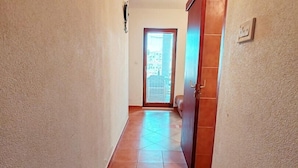 A hallway with a tiled floor leading to a door with a window.