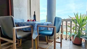 Un balcone con tavolo e sedie, un condizionatore d'aria e una pianta in vaso.
