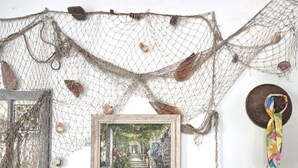 A bed with a white mattress and a yellow pillow, a framed picture on the wall, and a net decoration.