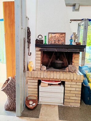 A brick-built outdoor oven with a shelf above it holding decorative items.
