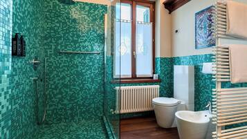 A modern bathroom with a glass-enclosed shower, a freestanding bathtub, a toilet, and a bidet.