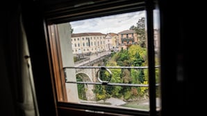 Vista a través de una ventana que muestra un puente, edificios y vegetación.