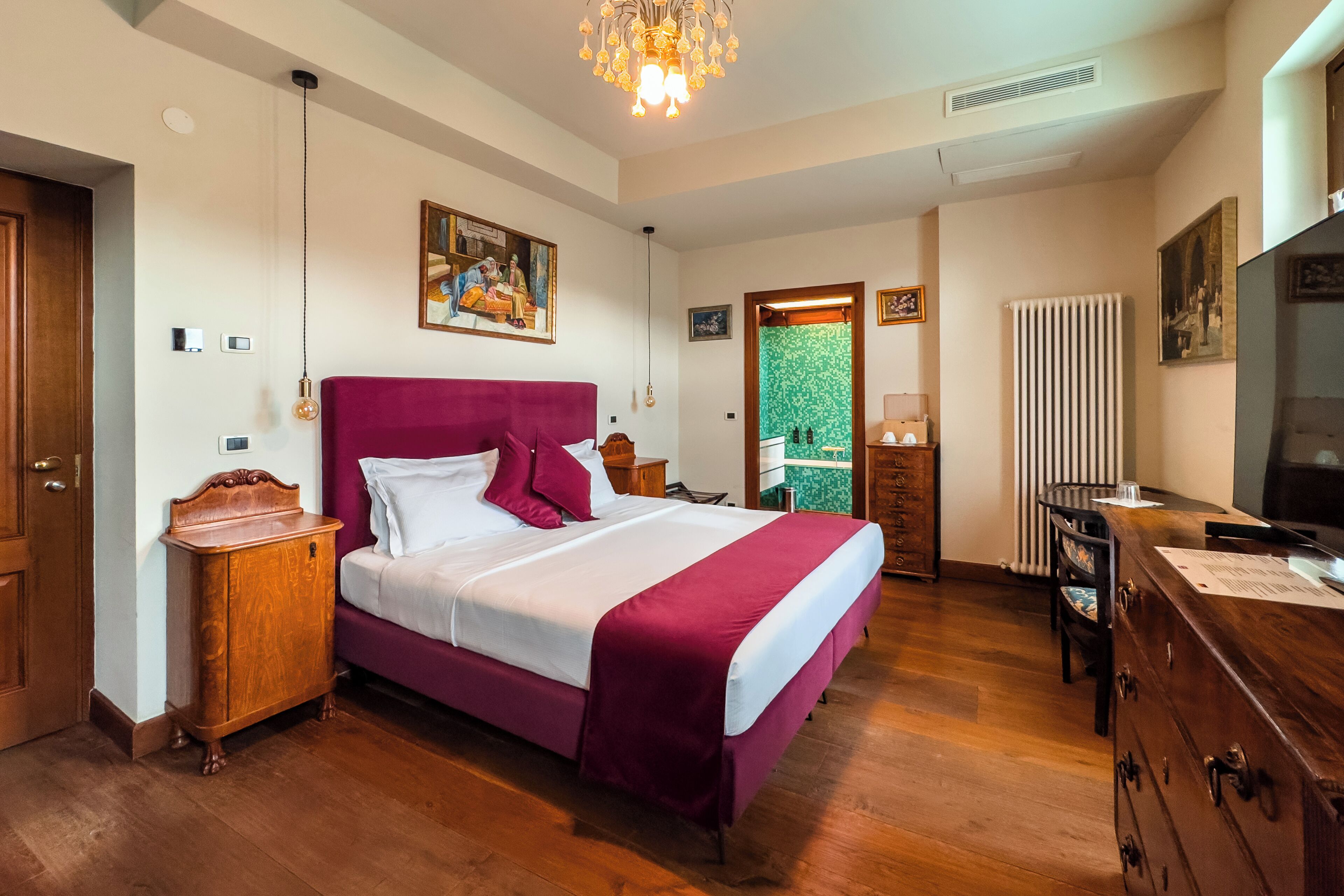 A bedroom with a large bed, wooden dresser, and a television.