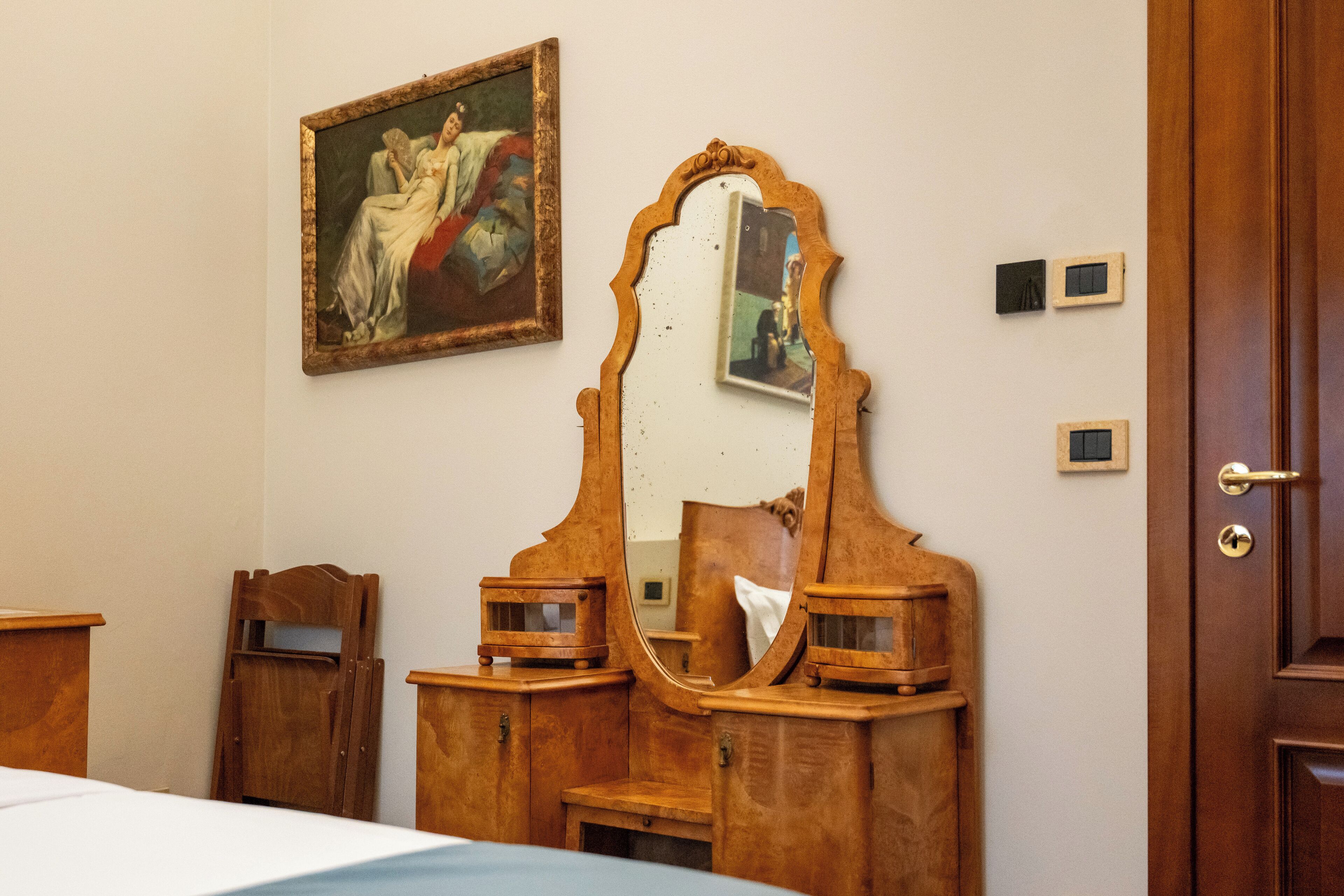A room with a wooden dresser, a large mirror, and a painting on the wall.