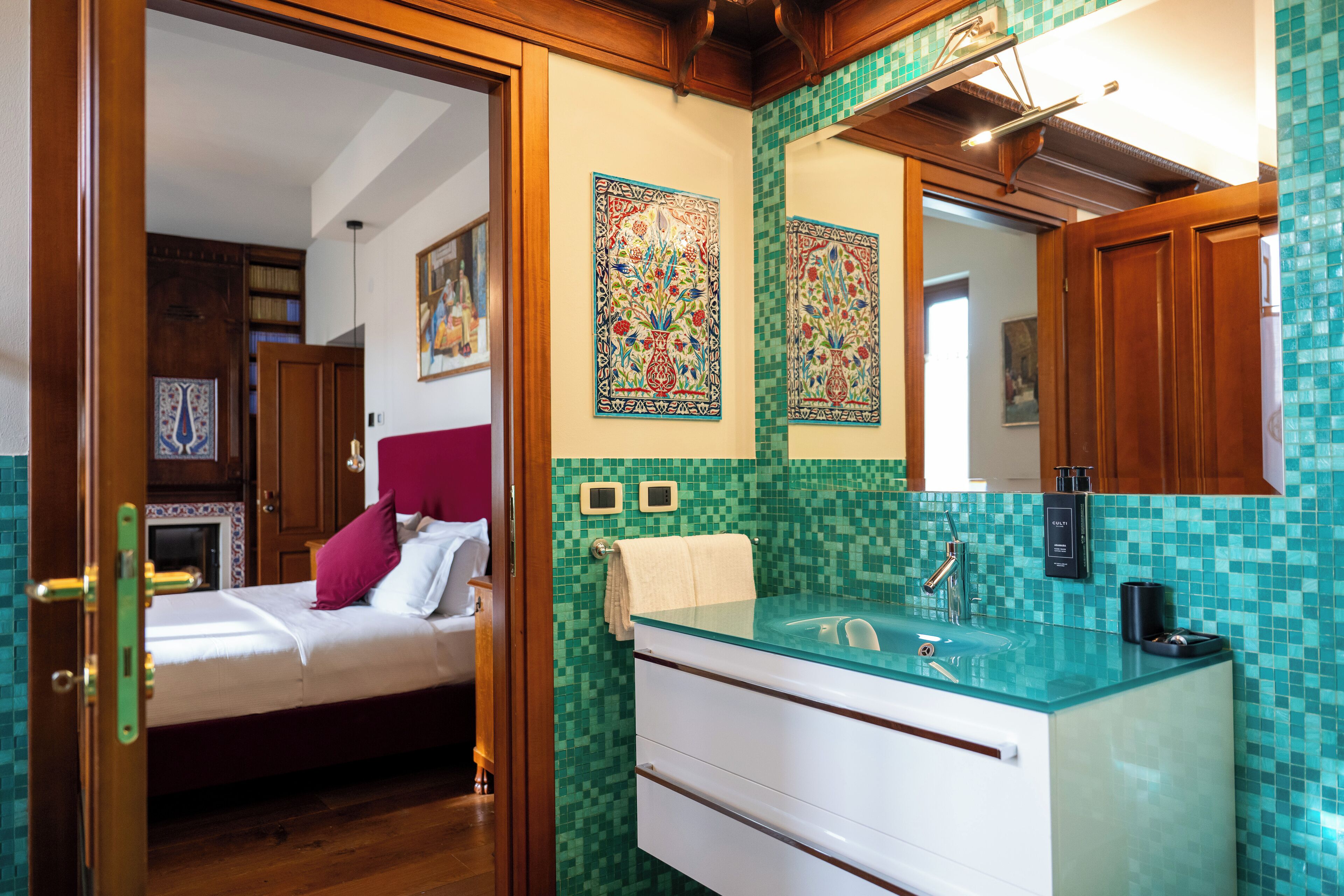 A hotel room with a bed, a bathroom with a glass sink, and a tiled backsplash.