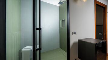 A modern bathroom with a glass shower enclosure, a toilet, and a built-in sink.