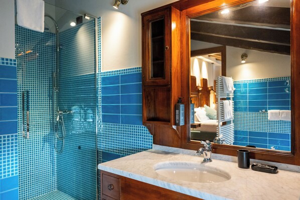 Une salle de bain avec un grand miroir, un lavabo et un espace douche aux carreaux bleus.