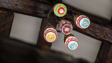 A ceiling with a wooden beam structure and colorful, mosaic-patterned lamps.