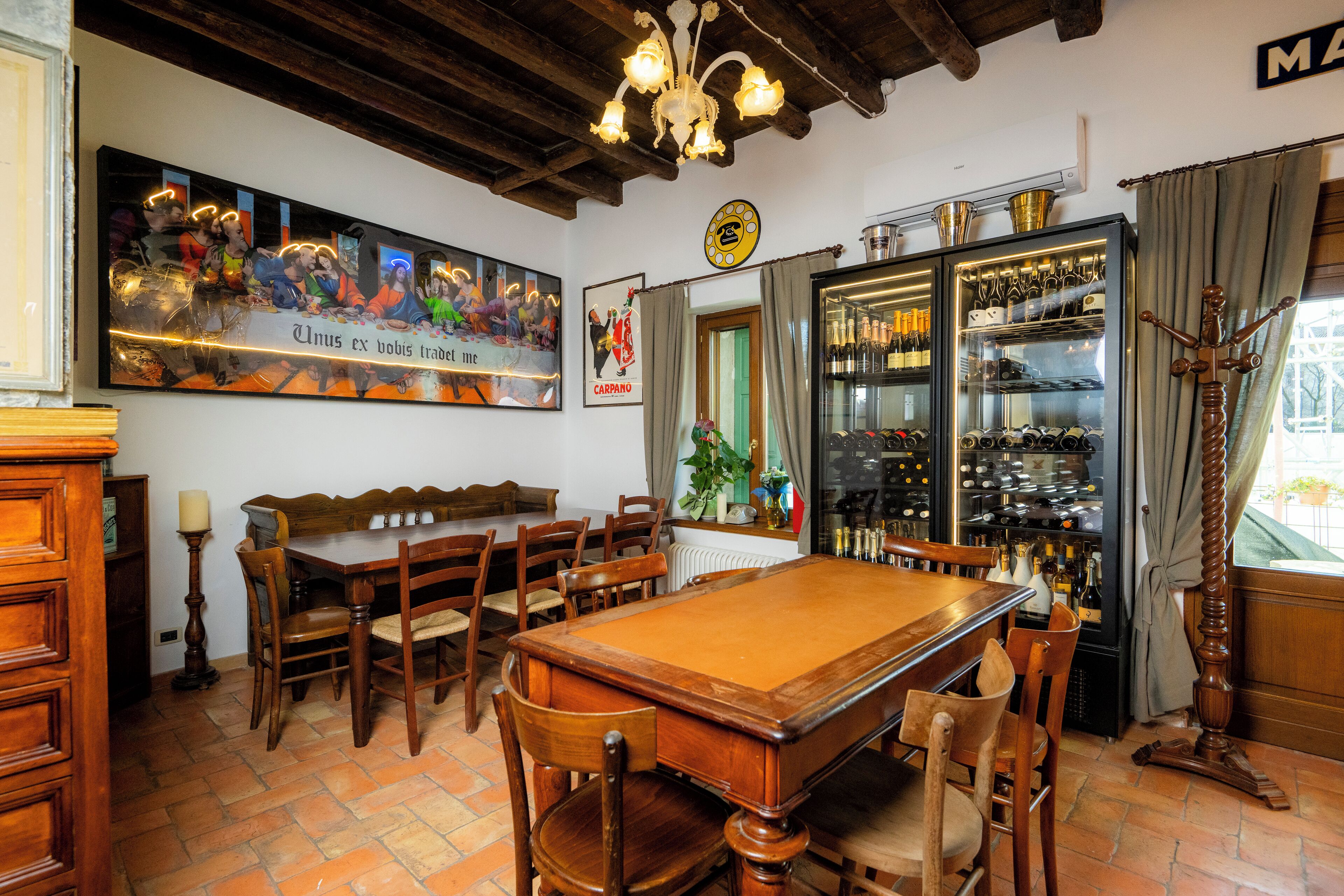 Une salle de billard équipée d’une table de billard, de chaises en bois, d’un coin bar avec des bouteilles de vin et d’une grande affiche accrochée au mur.