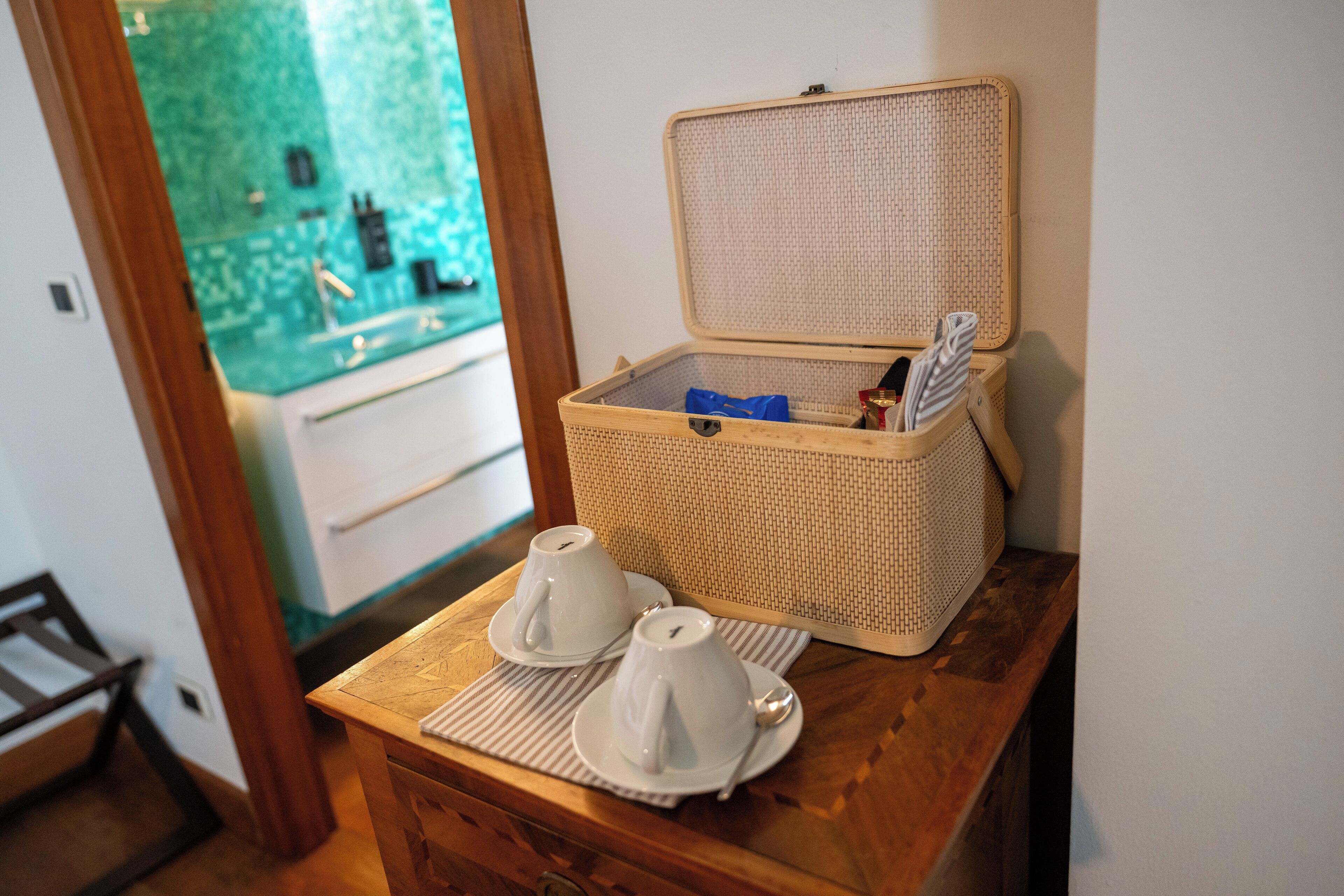 Taula de fusta amb una cistella de vimet que conté un objecte petit i una safata amb dues tasses i platets blancs.