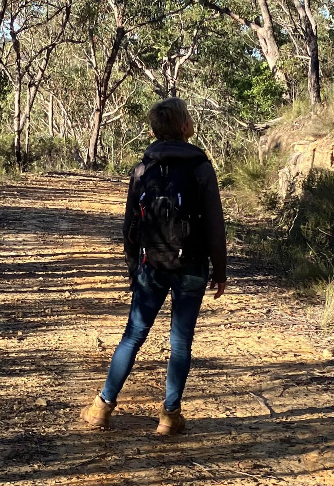 A person walking on a dirt path surrounded by trees.