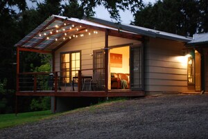 Uma casa com varanda coberta, painéis solares e interior iluminado.