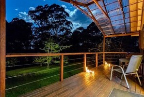 Um deck de madeira com teto de vidro, uma cadeira e uma mesa.