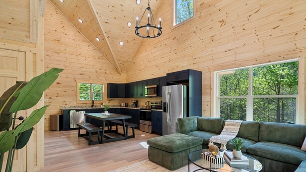 Un intérieur de chalet en bois spacieux, comprenant un coin repas, une cuisine et un salon.