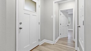 A hallway with white doors, light grey walls, and a wooden floor.