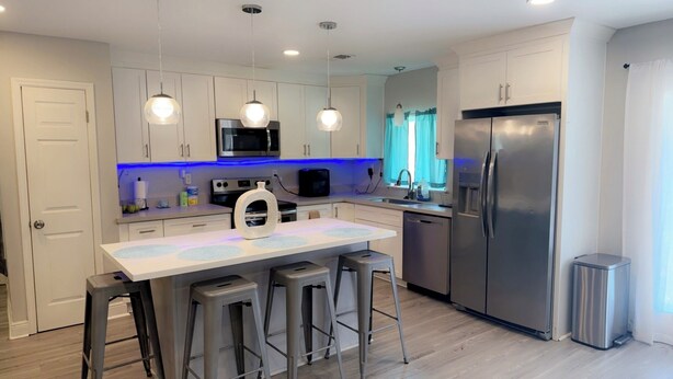 A modern kitchen with white cabinets, stainless steel appliances, and a central island with stools.