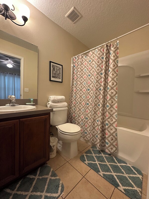 Un baño con lavamanos, inodoro y cortina de ducha.