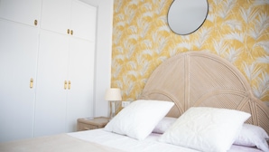 A bedroom with a bed, white wardrobe, and a nightstand with a lamp.