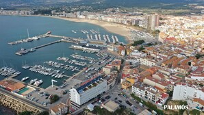An aerial view of a coastal city with a marina, buildings, and a beach.