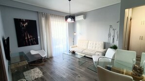 Una sala moderna con un sofá blanco, una mesa de centro de vidrio y un comedor con mesa y sillas de vidrio.