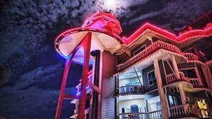 A building with a prominent red-lit tower and a balcony with railings. - The Silver Castle  (Mymensingh)