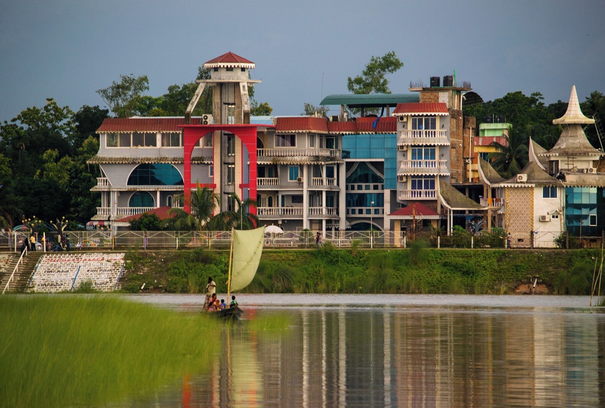 A waterfront building with multiple stories, balconies, and a tower.