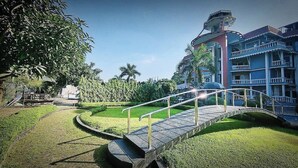 A hotel with a bridge, lush greenery, and a multi-story building with balconies. - The Silver Castle  (Mymensingh)