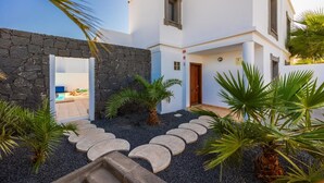 Um edifício moderno com parede de pedra, piscina e plantas tropicais.