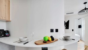 Eine moderne Küche mit einer weißen Kochinsel, Holzstühlen und einer Obstplatte.