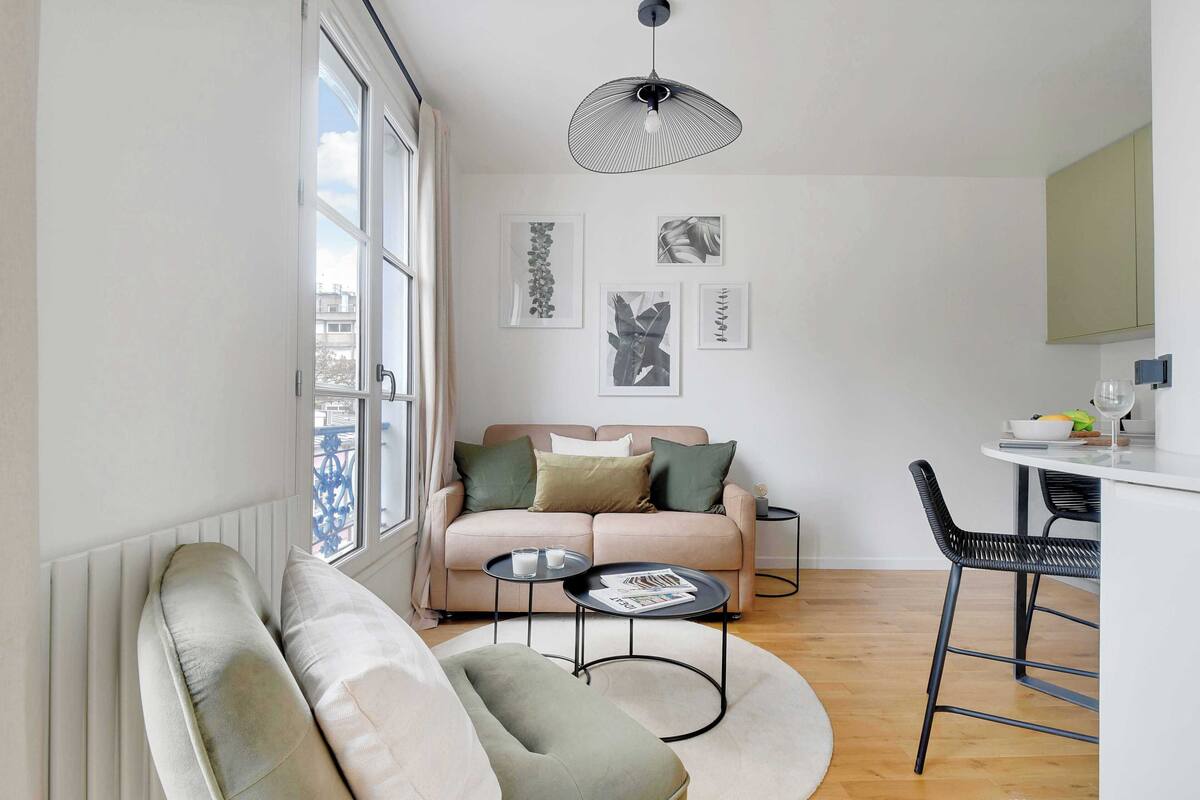 A modern living room with a sofa, a round coffee table, and a dining area with a bar stool.