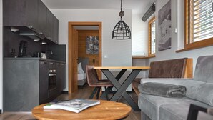 Una cocina moderna con armarios oscuros, una cafetera y un comedor con una mesa y sillas de madera.