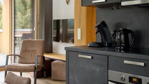 A modern kitchen with a coffee maker, a digital oven clock, and a wooden dining table with chairs. - 59111 Bartgeier 111 T (Gargellen)