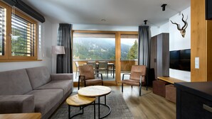 A modern living room with a sofa, two round tables, a TV, and a wooden cabinet. - 59111 Bartgeier 111 T (Gargellen)