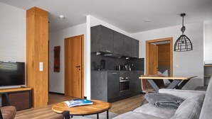 Ein modernes Wohnzimmer mit grauem Sofa, Couchtisch aus Holz und einem Fernseher.