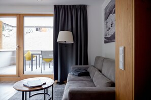 Relax in this stylish living room with a sofa, coffee table, and sliding door leading to an outdoor dining area.