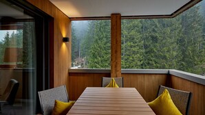 Una mesa de madera con cojines amarillos, un panel de vidrio y vistas a un bosque.