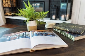 A book titled 'UNHOUSED' on a table with a potted fern and a magazine. - Poconos Chatham Continental - Hot Tub & Fire Pit (Bushkill)