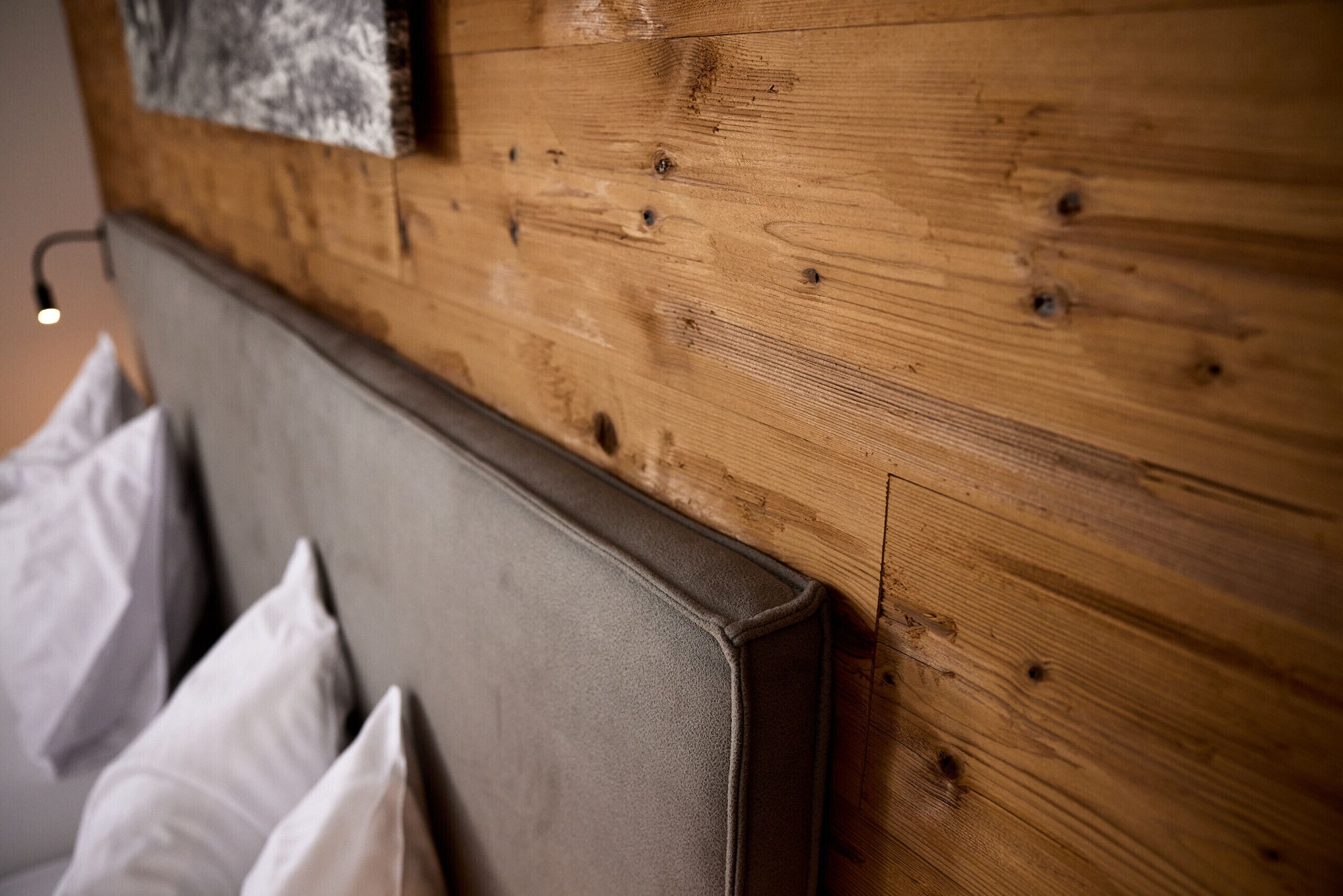 A wooden headboard with a textured finish and a light switch on the wall.