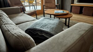 Ein modernes Wohnzimmer mit einer Couch, Sesseln, einem Couchtisch und einem Fernseher.