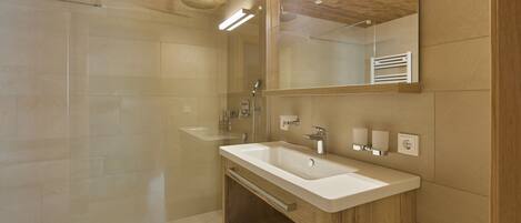 A modern bathroom with a wooden ceiling, a glass shower enclosure, and a double sink vanity.