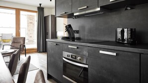 Eine moderne Küche mit dunklen Schränken, einem eingebauten Backofen und einer Kaffeemaschine.