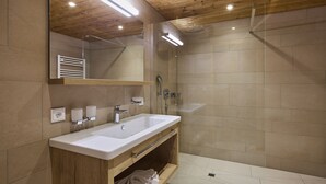 A modern bathroom with a wooden vanity, a large mirror, a shower, and a tiled floor. - 59217 Wanderfalke 217 T (Gargellen)