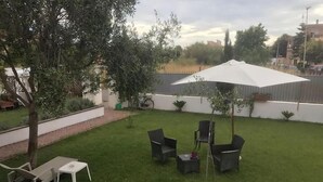 A backyard with a lawn, a white umbrella, and outdoor furniture. - Alloggio Turistico (Fiumicino)