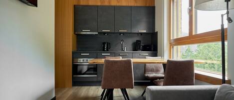 Una cocina moderna con armarios oscuros, encimera de madera y una zona de comedor con dos sillas.